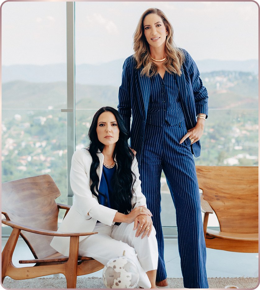 Sócias da Amlak Kallab, com postura confiante e trajes formais, transmitindo solidez e profissionalismo. Ao fundo, vista panorâmica da cidade aparece pelas janelas de vidro
